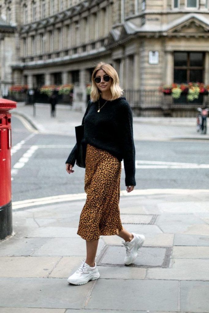 Image montrant une femme portant une jupe longue et fluide motifs léopard avec des dad shoes blanches.